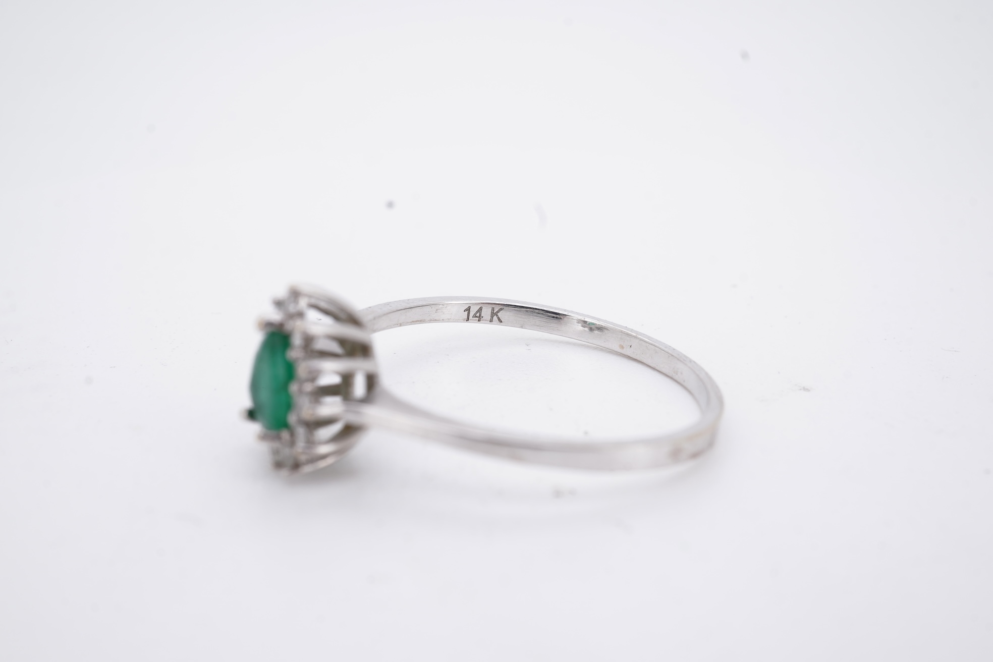 A modern white metal(stamped 14k), emerald and diamond set pear shaped cluster ring, size R, gross weight 1.3 grams.